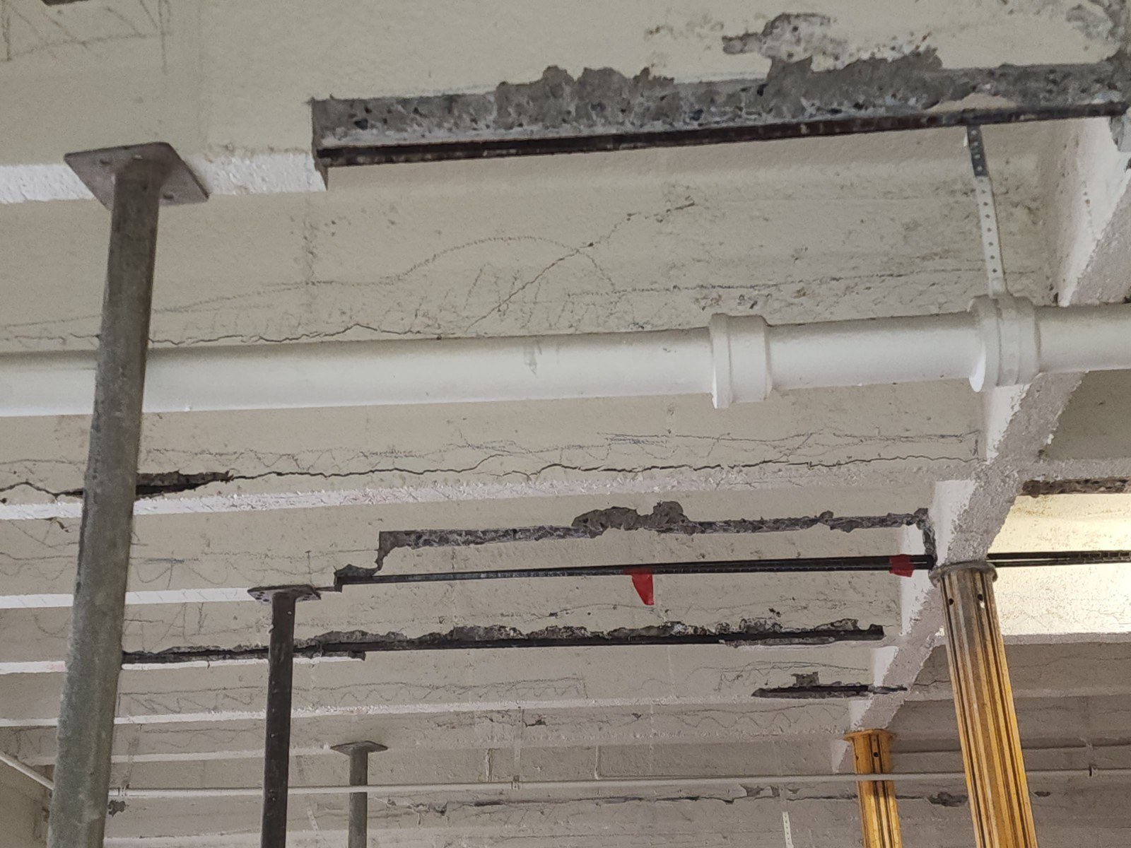 Spalled garage slab with exposed rebar and shoring during concrete restoration