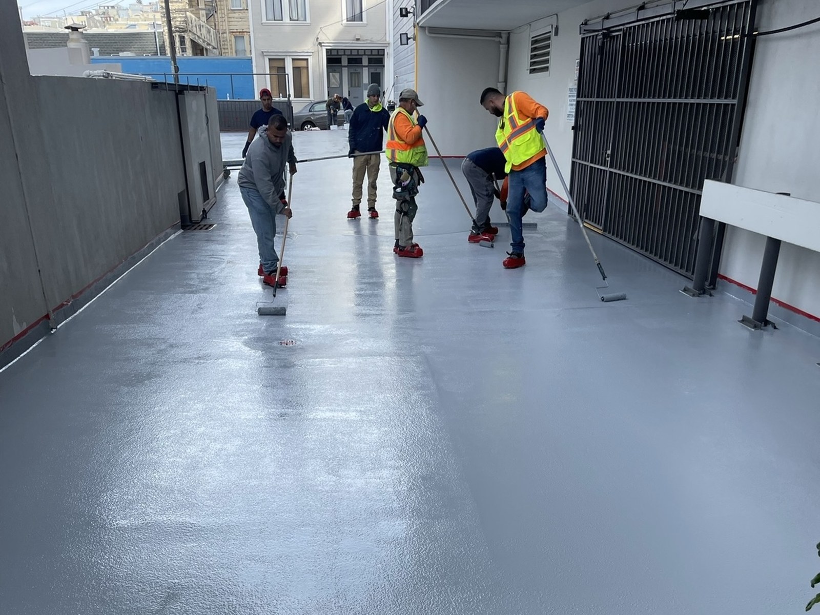 Crew rolling a waterproof coating on a plaza deck